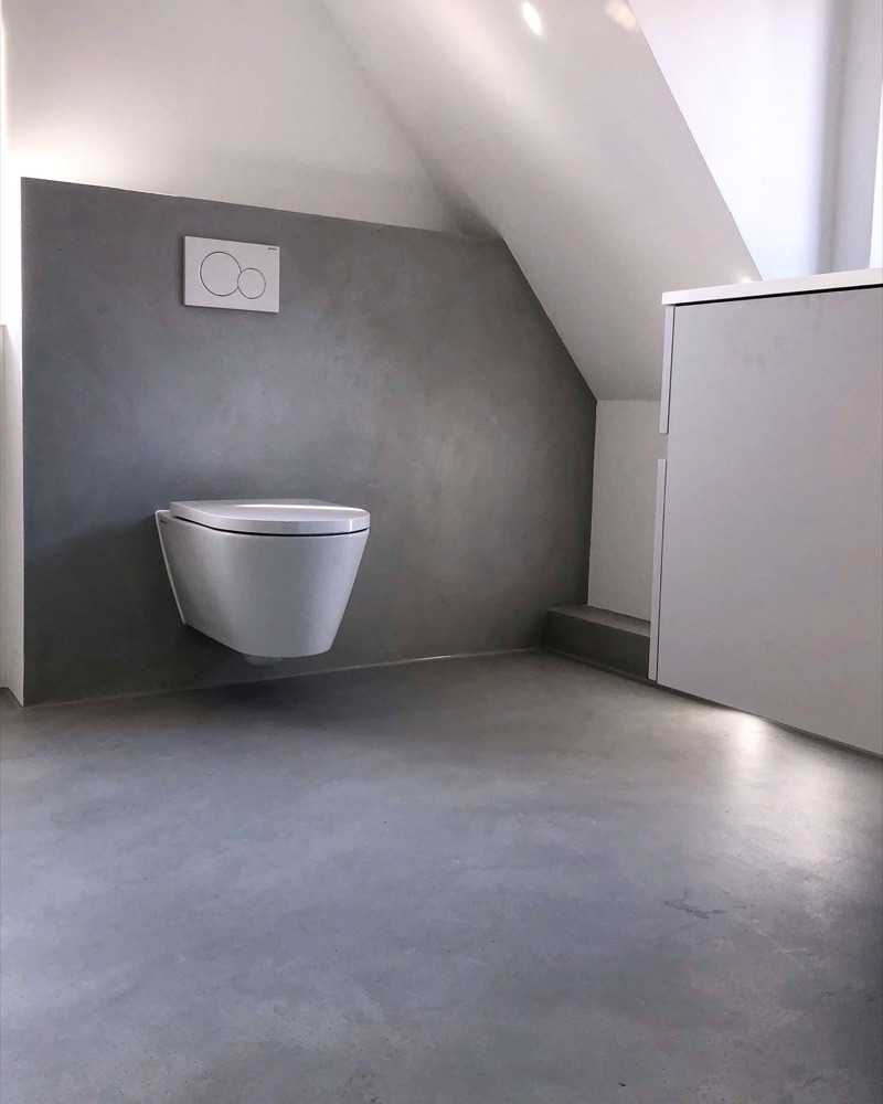 Graues Badezimmer mit fugenlosen Mikrozementflächen an Wand und Boden