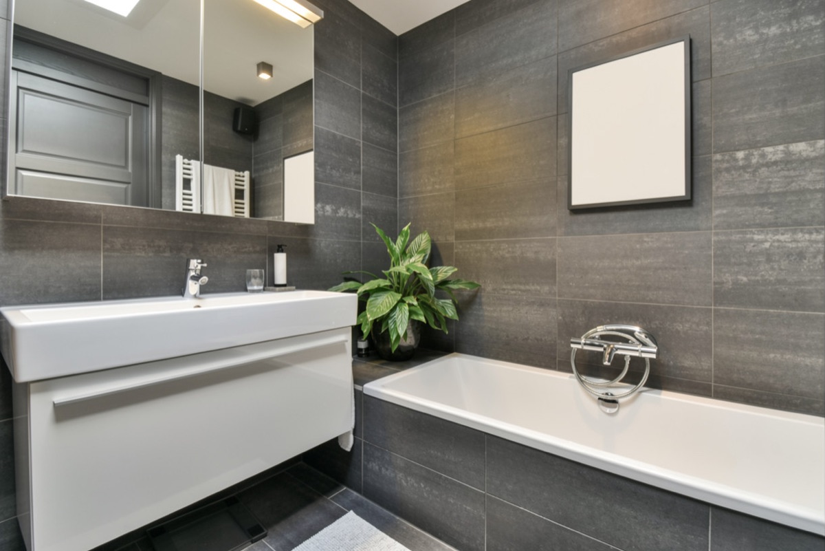 Modernes Bad mit grauen Fliesen, Badewanne und Waschtisch